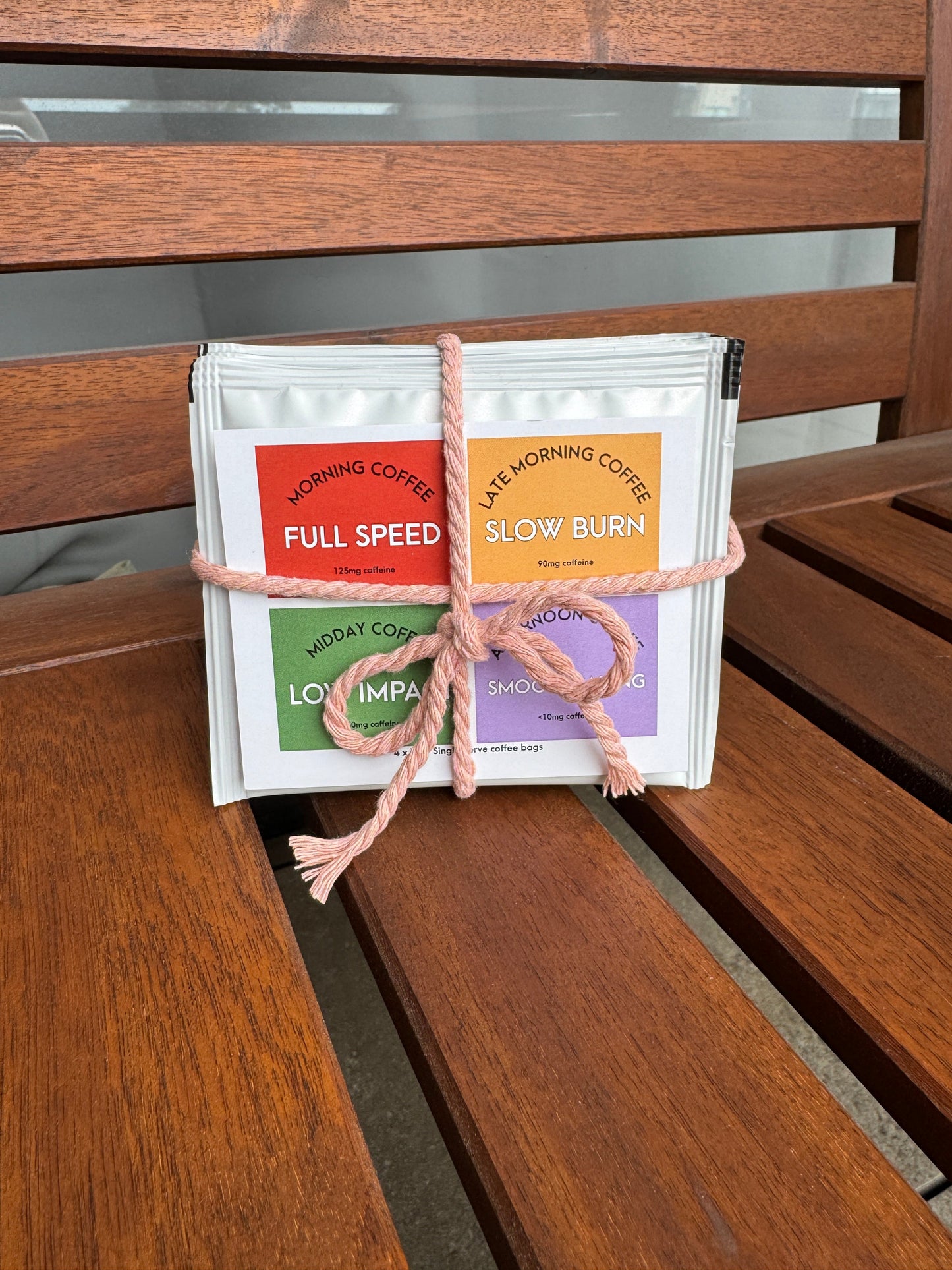 Stack of coffee bags with labels tied together on a wooden surface